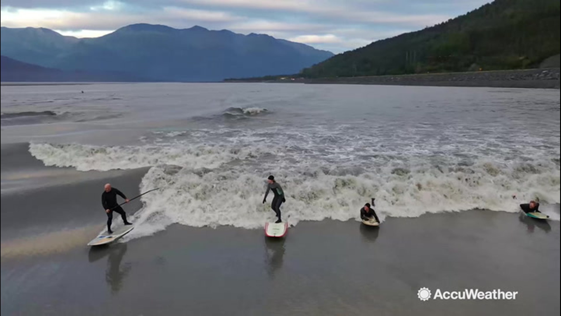 A tidal wave rolls up on Turnagain Arm, Alaska, with every high tide.  At certain parts, the wave is perfect for surfing and creates a surreal scene of surfers surrounded by snow-capped peaks.